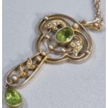 15ct gold Art Nouveau design peridot and Seed Pearl pendant on a 9ct gold chain. 6.4g approx. (B.