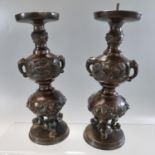 Pair of Japanese bronze tripod candlesticks with panels of birds in branches and bull's head at