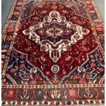 Rich red blue ground Persian Bakhtiari village rug with large central floral and foliate