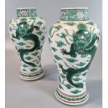 A pair of Chinese porcelain baluster vases, each decorated with two dragons amidst stylised clouds