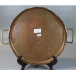 Arts & Crafts design copper repousse two handled tray with brass handles, of circular form, with