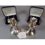 A pair of silver dwarf candlesticks with loaded bases. Birmingham hallmarks. Together with two cased
