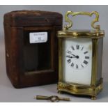 Early 20th Century brass carriage clock in fitted leather case, with enamel face and Roman