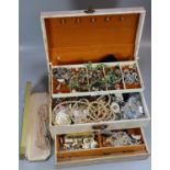 Cream cantilever jewellery case containing a large assortment of costume jewellery. (B.P. 21% + VAT)