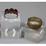 9ct gold three stone garnet dress ring and a gold plated wedding ring. (2) (B.P. 21% + VAT)