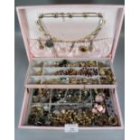 Pink coloured cantilever jewellery box containing a large collection of vintage costume jewellery of