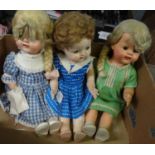 Three plastic children's dolls with moveable eyes and limbs in fabric clothing: one in woolen