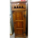 Stained pine tall pedestal cupboard with pierced geometric frieze and panelled door. 50cm wide