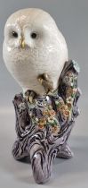 Continental porcelain study of a white owl on naturalistic tree stump with flowers and foliage.