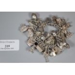 Silver charm bracelet with a large collection of assorted charms. 4 troy ozs approx. (B.P. 21% +