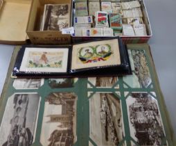 Collection of postcards in albums and in a box including WWI silk cards and tin of cigarette and tea