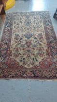 Persian design carpet on a cream and navy ground decorated with flowers and foliage. 203x132cm