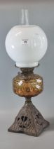 Early 20th century double oil burner lamp having globular opaline glass shade above an amber glass