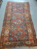 Kurdish rug on a red ground decorated with stylised geometric panels and medallions. 225x120cm