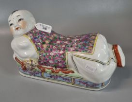 Chinese slip cast porcelain polychrome decorated pillow modelled as a reclining figure of a boy.