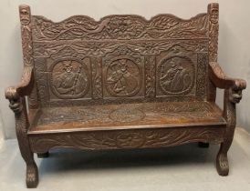 19th century oak Flemish style settle, the shaped back with carved decoration of mask heads and