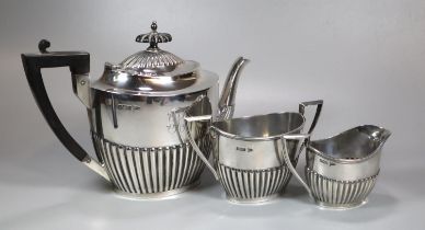 Edward VII silver fluted three piece service, the teapot with geometric ebonised handle, to include: