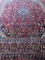 Red and blue ground Persian Kashan carpet with traditional designs, central medallion, flanked by