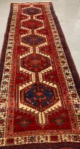 Red ground Persian Heriz runner originating from Northern Iran with repeating central medallions,