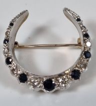 White and yellow metal seventeen stone diamond and sapphire crescent brooch. 6.8g approx. (B.P.