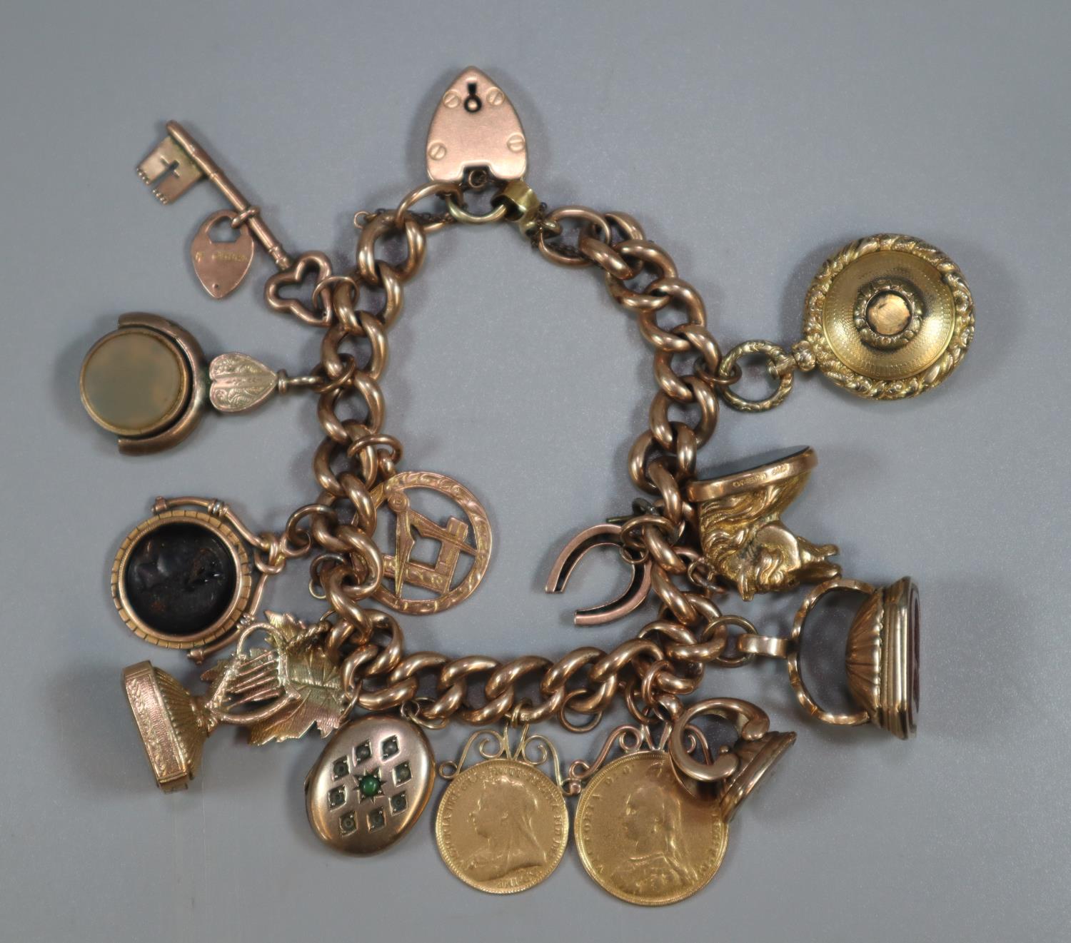 9ct gold curb link charm bracelet with assorted charms including: Masonic, harp, Intaglio seal