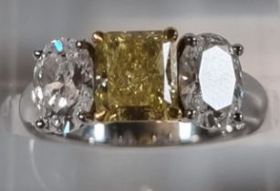 18ct white gold fancy grade three stone diamond ring, the central stone drawing yellow colour, two