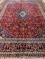 Large fine hand woven Iranian carpet on a red and navy ground with large central medallion. Kashan