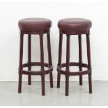 A set of two stained wood and burgundy leather, round bar stools