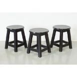 A set of three black painted wooden stools