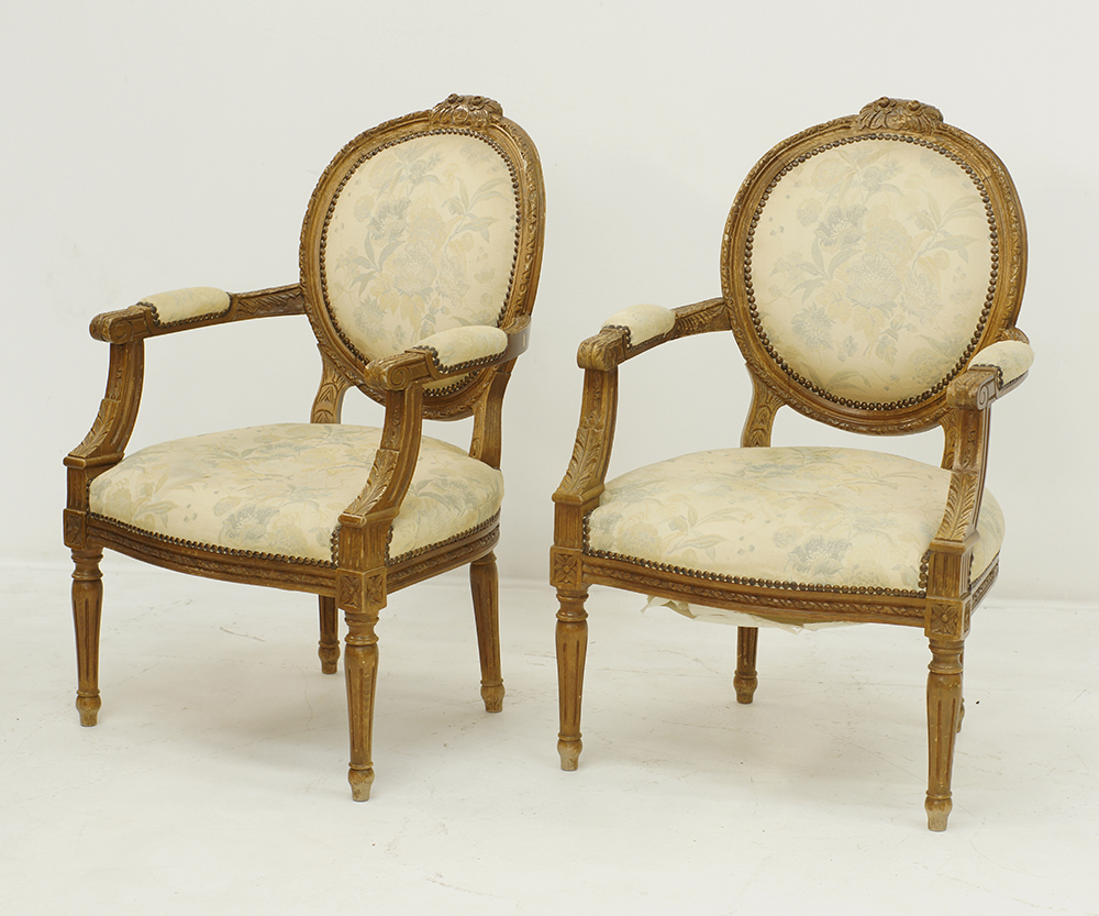 A pair of carved Louis XVI style open armchairs