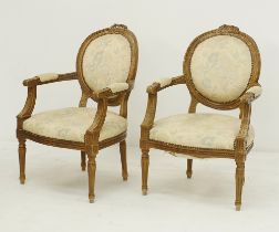 A pair of carved Louis XVI style open armchairs