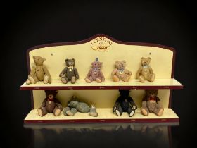 A COLLECTION OF NINE 'A CENTURY OF STEIFF' PORCELAIN TEDDY BEARS. WITH COLLECTORS DISPLAY SHELF.