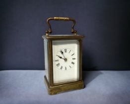 A LATE VICTORIAN BRASS CARRIAGE CLOCK. FIVE BEVEL EDGED GLASS PANELS. WHITE ENAMEL DIAL WITH BLACK