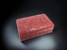 A CHINESE RED LACQUER BOX. QING DYNASTY. CARVED LIONS AMONGST ROCKY OUTCROP. 14.5 X 5 X 9.5CM