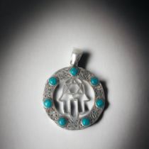 A SILVER FILIGREE 'HAND OF MIRIAM' PENDANT. SET WITH TURQUOISE. DIAMETER - 40MM