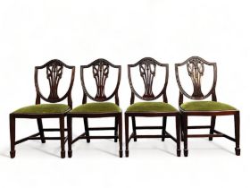 A set of four Mahogany Chippendale style dining chairs. With carved stylised fleur-de-lis back.