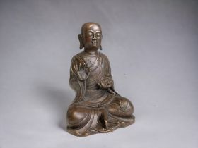 A Chinese Tibetan bronze seated figure of Buddha. Qing dynasty. Holding a mouse & pearl. Height -