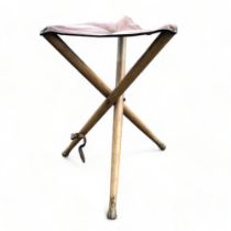 A vintage folding leather tripod stool.