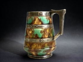 WEDGWOOD TANKARD WITH SILVER PLATE MOUNTED BANDS AND EGYPTIAN DESIGN HANDLE OVER MOTTLED GLAZE.