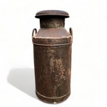 A large industrial metal 'United Dairies' milk churn.