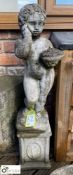 A reconstituted stone Cherub holding a basket of f