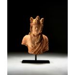 A GANDHARA TERRACOTTA BUST OF A CROWNED KING, CIRCA 5TH CENTURY CE OR LATER