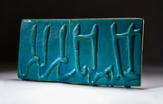 A TURQUOISE GLAZED CALLIGRAPHY TILE, KASHAN, CIRCA 12TH CENTURY, PERSIA