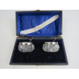 Pair of G E Walton birmingham 1905 silver rimmed glass salts and spoons. One is cracked.