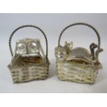 2 Sets of white metal napkin rings in the form of Cats and owls sat in carrying baskets.