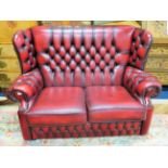 Two seat Chesterfield wing back settee, beautifully upholstered in Oxblood leather. Excellent condit