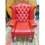 Leather upholstered Chesterfield wing back chair. Raised on short cabriole legs which have been thou