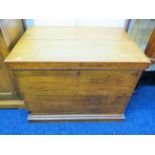 Light oak blanket box/chest. Lifting lid. Large brass carry handles to side standing on a plinth bas