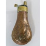 Vintage copper powder flask with embossed eagle design.