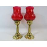 2 brass candlesticks with cranberry glass shades, approx 11" tall.